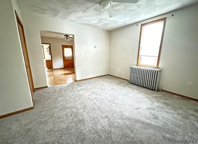 carpeted empty room with radiator heating unit and ceiling fan