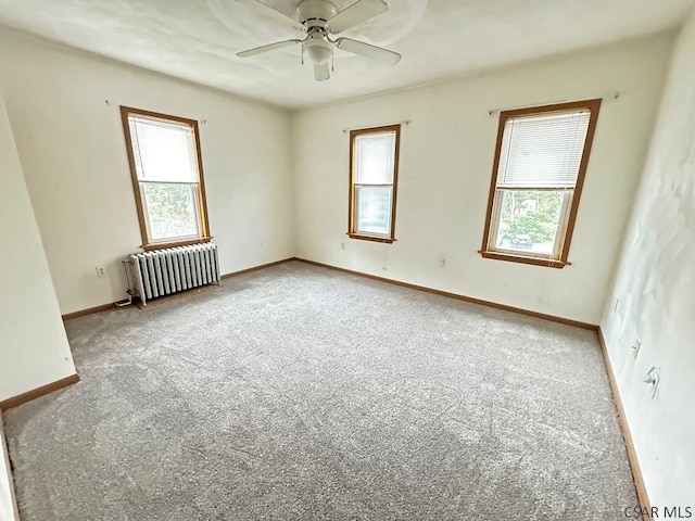 carpeted empty room with radiator and ceiling fan