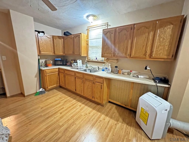 kitchen with ceiling fan, sink, a textured ceiling, and light hardwood / wood-style floors