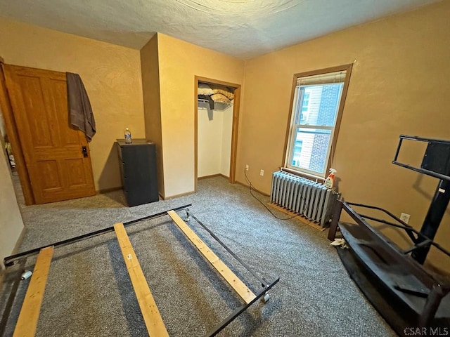 unfurnished bedroom featuring carpet flooring, radiator, a textured ceiling, and a closet