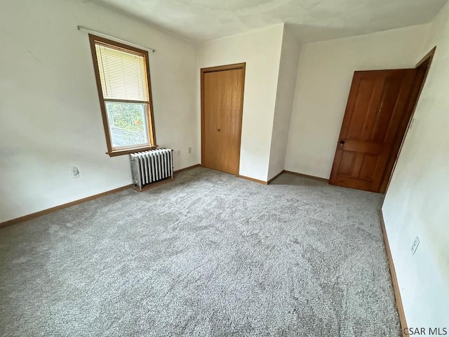 unfurnished bedroom with a closet, radiator, and carpet flooring