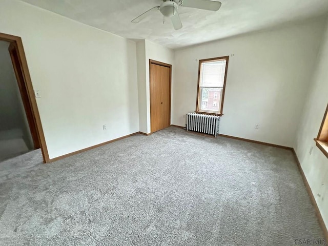 unfurnished room with ceiling fan, radiator heating unit, and carpet floors