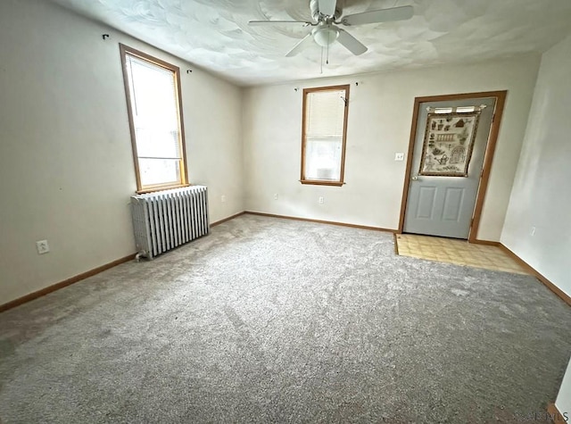 carpeted spare room featuring radiator heating unit and ceiling fan