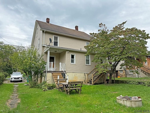 rear view of property with a fire pit and a lawn