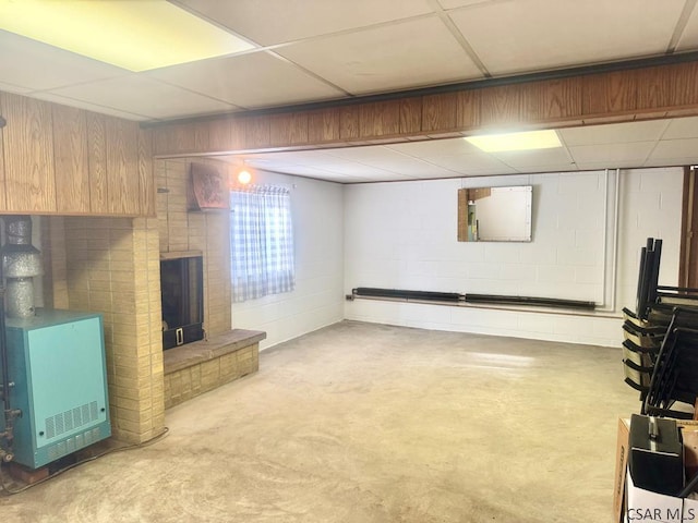 basement featuring a brick fireplace, a paneled ceiling, and concrete block wall