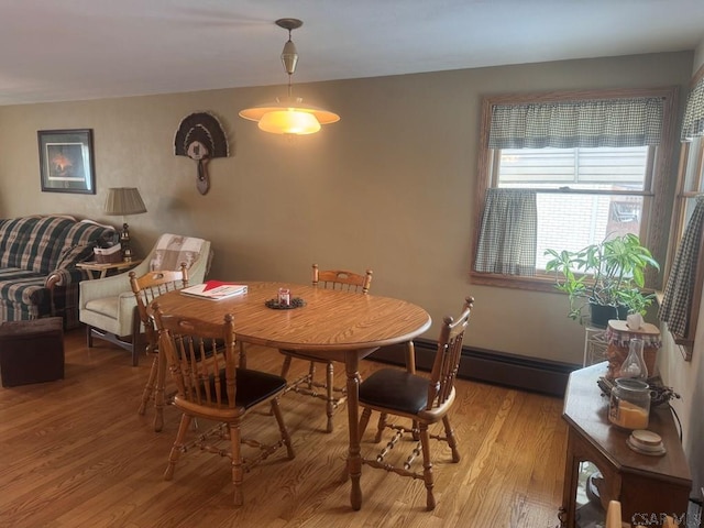 dining space with baseboards, baseboard heating, and light wood-style floors