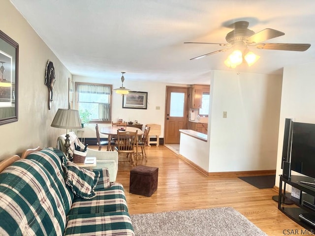 living area featuring light wood-type flooring, baseboards, and a wealth of natural light