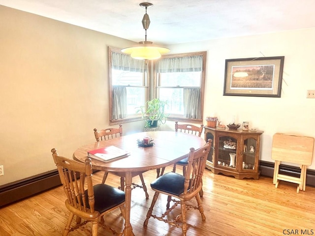 dining space featuring a baseboard radiator, light wood-style flooring, and baseboards