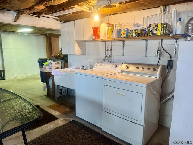 laundry area with concrete block wall, laundry area, a sink, and washing machine and clothes dryer