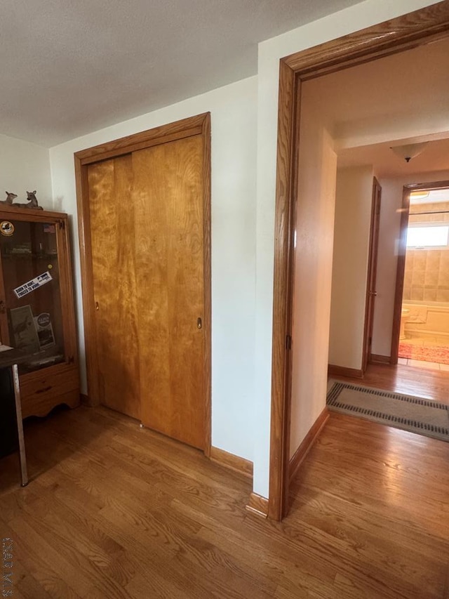 corridor with baseboards, baseboard heating, and wood finished floors