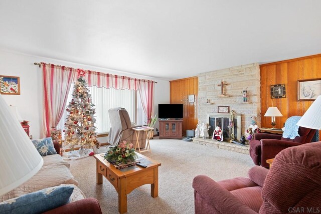 living room featuring a fireplace, wooden walls, and carpet flooring