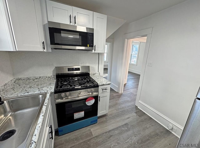 kitchen featuring appliances with stainless steel finishes, light stone countertops, sink, and white cabinets