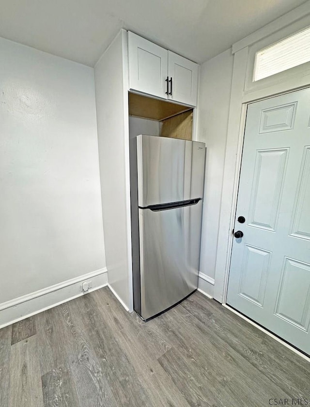 kitchen with white cabinetry, stainless steel fridge, and light hardwood / wood-style floors