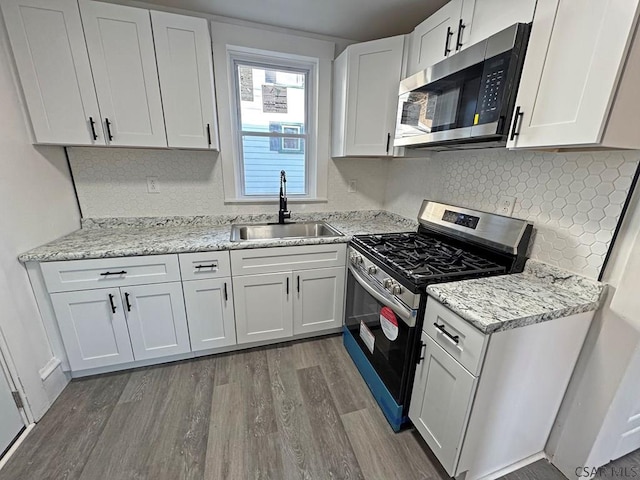 kitchen with sink, appliances with stainless steel finishes, tasteful backsplash, white cabinets, and dark hardwood / wood-style flooring