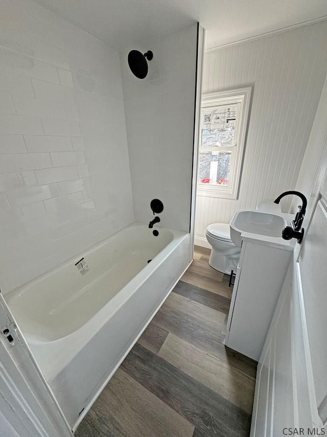 full bathroom with tiled shower / bath combo, wood-type flooring, vanity, and toilet