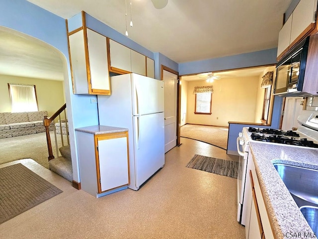 kitchen featuring white appliances, a ceiling fan, open floor plan, and light countertops