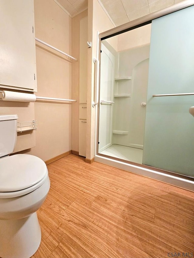 full bathroom with a shower stall, toilet, wood finished floors, and baseboards