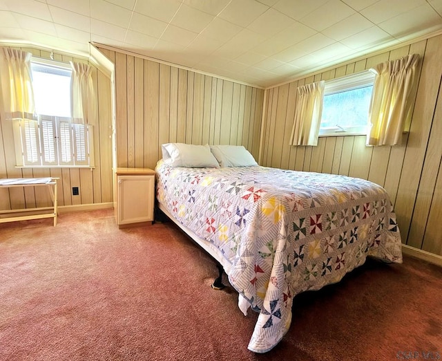 carpeted bedroom featuring wooden walls and multiple windows