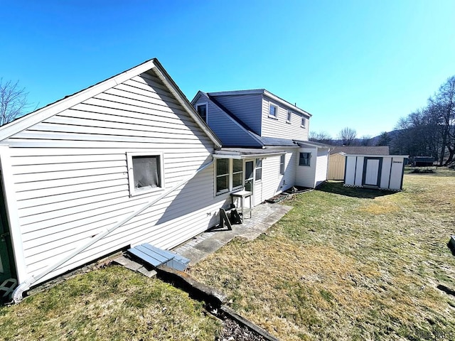 rear view of house featuring an outbuilding, a storage unit, and a yard