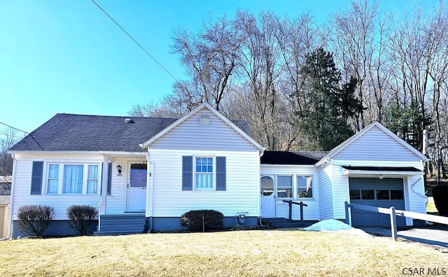 ranch-style house with entry steps, an attached garage, a front lawn, and roof with shingles