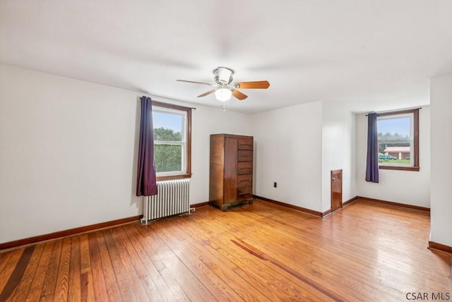 empty room with radiator, ceiling fan, and light hardwood / wood-style flooring