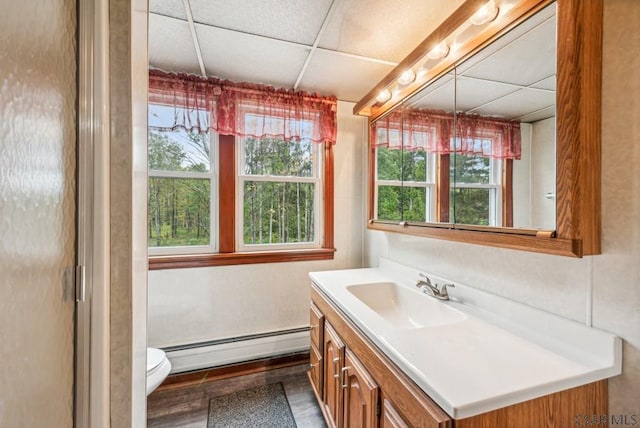 bathroom with vanity, a baseboard heating unit, a paneled ceiling, and toilet