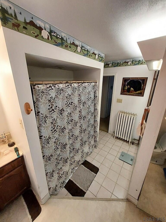 full bath featuring a textured ceiling, a shower with curtain, vanity, and radiator