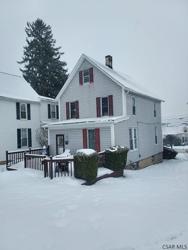 snow covered back of property with a chimney