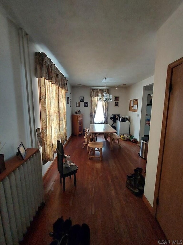 dining area with dark wood-style floors, radiator, a notable chandelier, and baseboards