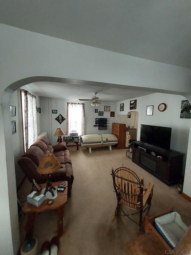 living room featuring carpet floors, arched walkways, and ceiling fan