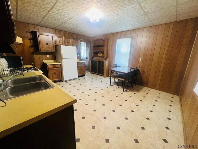 kitchen featuring sink, wood walls, and white fridge