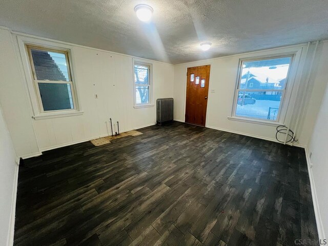 foyer entrance with dark hardwood / wood-style flooring, radiator heating unit, and a textured ceiling