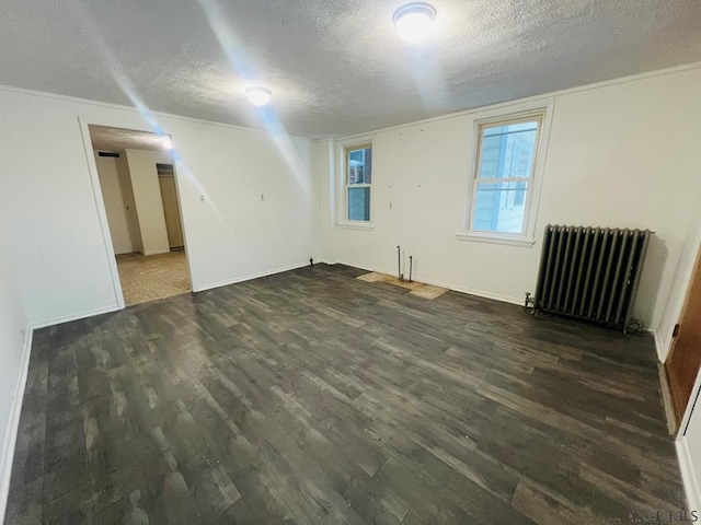 empty room with dark wood-type flooring, radiator, and a textured ceiling