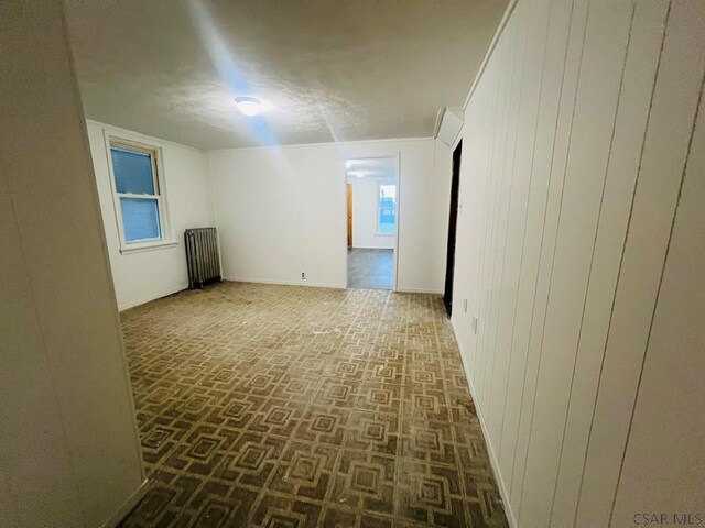 empty room with radiator heating unit and wooden walls