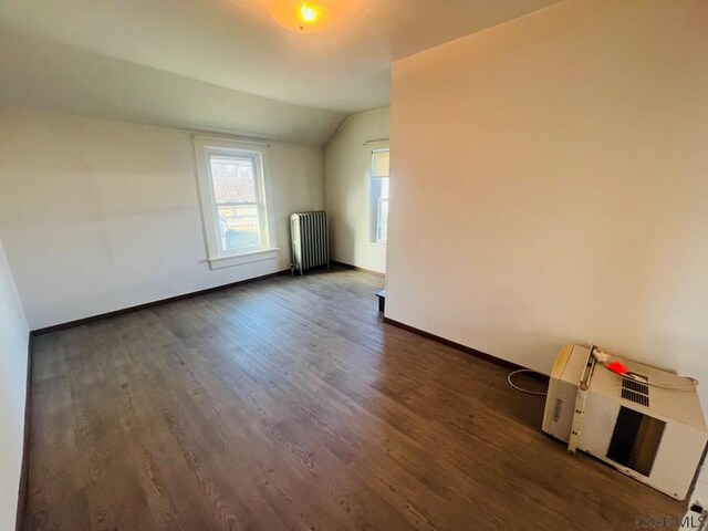 unfurnished room featuring vaulted ceiling, radiator, and dark hardwood / wood-style floors