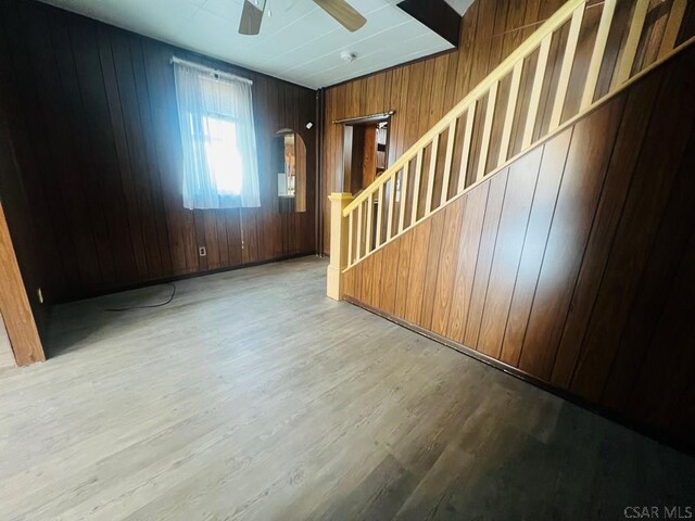 entryway with ceiling fan, light wood-type flooring, and wood walls