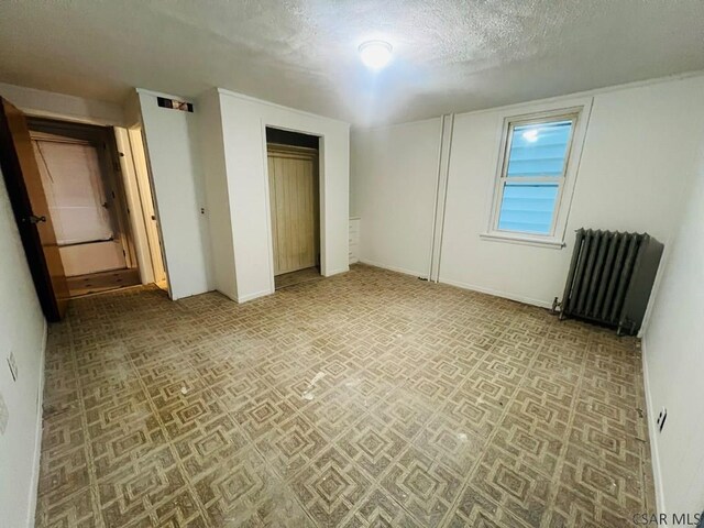 unfurnished bedroom featuring radiator and a textured ceiling