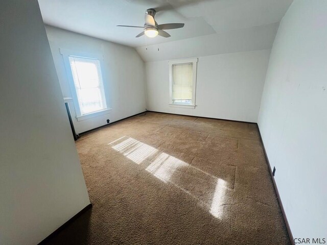 carpeted spare room featuring lofted ceiling and ceiling fan