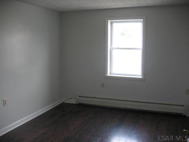 spare room featuring a baseboard radiator and dark hardwood / wood-style flooring