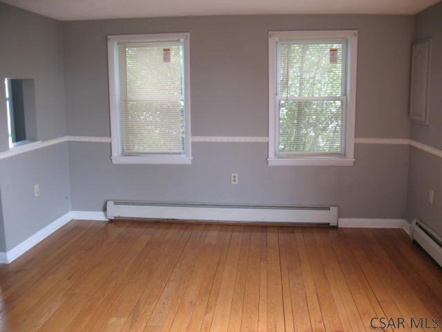 unfurnished room featuring wood-type flooring and baseboard heating