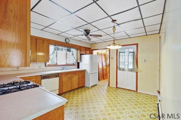 kitchen featuring white appliances, plenty of natural light, hanging light fixtures, and a drop ceiling