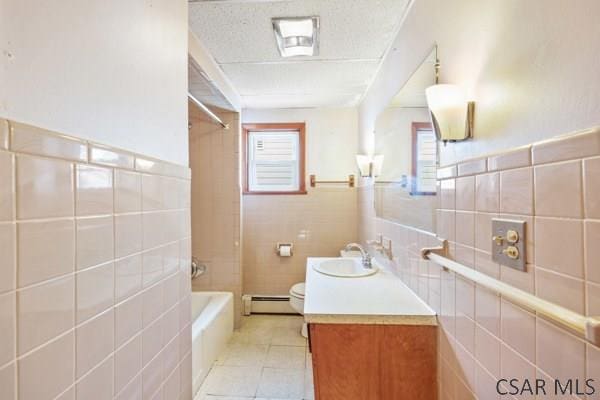 full bathroom with tile walls, vanity, a baseboard radiator, shower / bathtub combination, and toilet