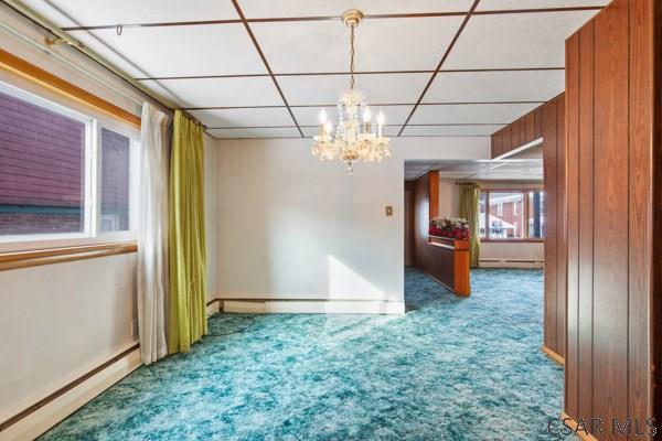 carpeted empty room featuring a baseboard heating unit