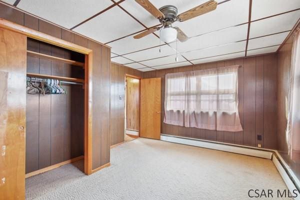 unfurnished bedroom featuring ceiling fan, a baseboard radiator, light carpet, and a closet