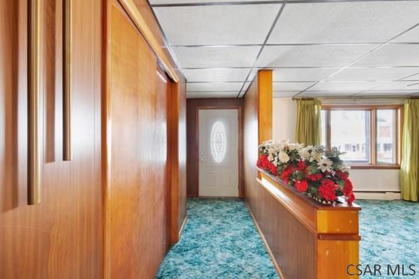 interior space with a baseboard heating unit, light colored carpet, and a drop ceiling