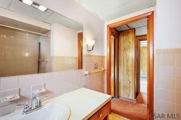 bathroom featuring tile walls, vanity, and tiled shower