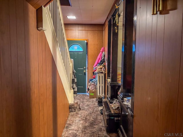 corridor featuring wood walls, stairway, and carpet flooring