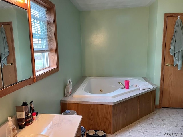bathroom featuring a jetted tub, vanity, and plenty of natural light
