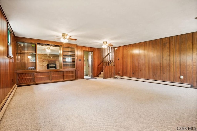 258 Samuels Rd, Somerset, PA 15501 - unfurnished living room with baseboard heating, wood walls, stairs, a ceiling fan, and carpet floors