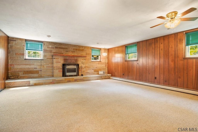 258 Samuels Rd, Somerset, PA 15501 - unfurnished living room featuring a baseboard heating unit, a fireplace, wooden walls, ceiling fan, and carpet flooring